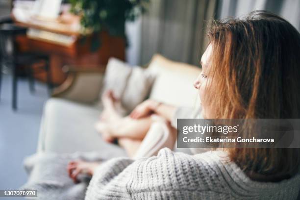 a young woman lies on a sofa with a cup of tea in her hands in a beautiful home interior - hygge stockfoto's en -beelden