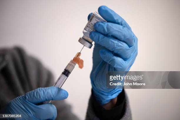 Nurse manager Lucy Golding draws up doses of the Moderna COVID-19 vaccine before health workers administered the shots to immigrants and undocumented...
