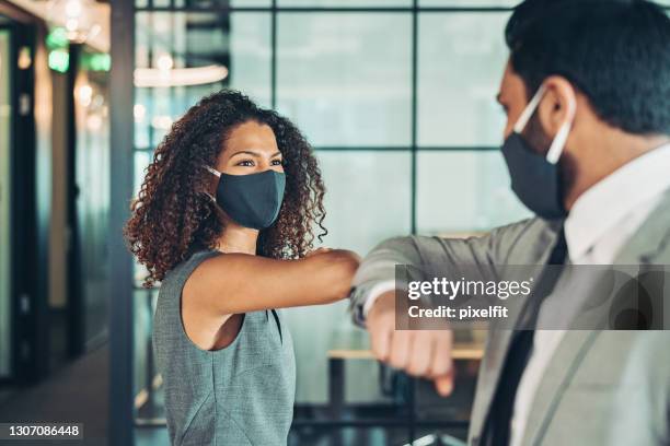 colleagues greet in the office during the covid-19 pandemic - touching elbows stock pictures, royalty-free photos & images