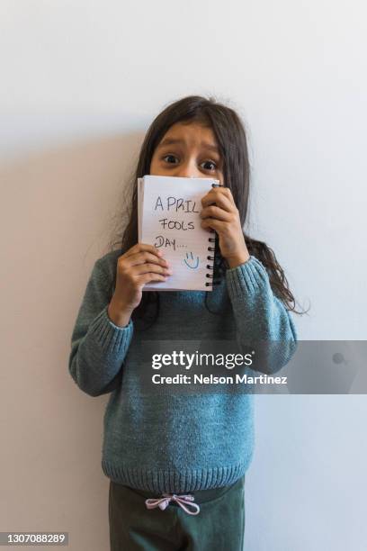 little girl holding a notebook in which puts aprils fool day - april fools day stock pictures, royalty-free photos & images