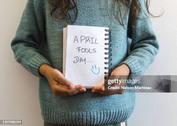 little girl holding a notebook in which puts aprils fool day - april fool photos et images de collection