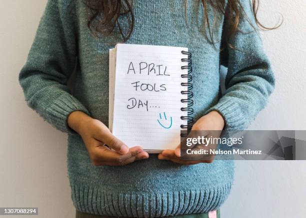 little girl holding a notebook in which puts aprils fool day - april fools day 個照片及圖片檔