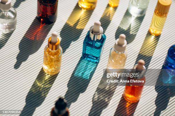 set of three glass vials on striped ultimate gray background. concept of skin care procedures for health and wellbeing. sunlight makes shadows and illuminating reflections from bottles. flat lay style. trendy colors of the year 2021 - parfum stock-fotos und bilder