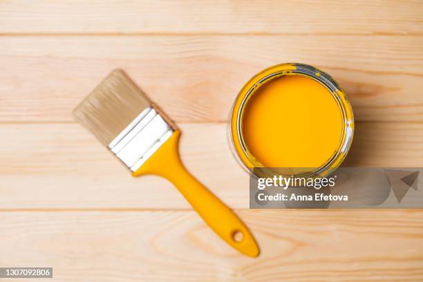 clean paintbrush next to futuristic gray metal bucket with bright illuminating yellow paint for renovation works on lumber floor. flat lay style. copy space for your design. concept of redecoration in home interior. color swatch for design ideas. trendy c - diy top view stock pictures, royalty-free photos & images