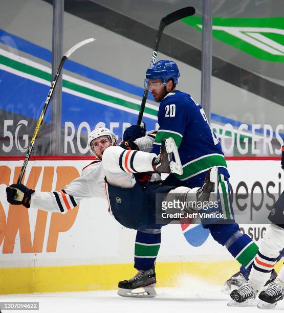 Brandon Sutter of the Vancouver Canucks checks Connor McDavid of the Edmonton Oilers during their NHL game at Rogers Arena on March 13, 2021 in...