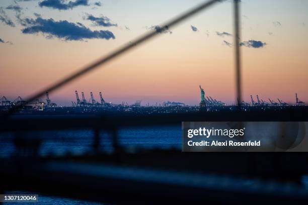 View of The Statue of Liberty during the first sunset after the clocks changed for Daylight Savings as seen from the Brooklyn Bridge on March 14,...