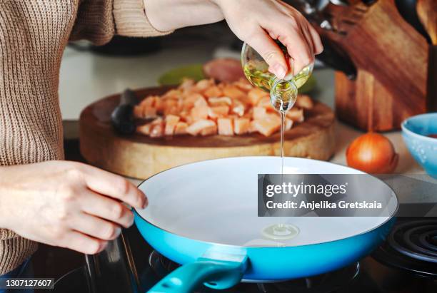 woman pouring olive oil into the skillet. - huile de table photos et images de collection