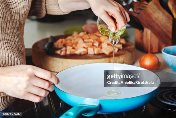 woman pouring olive oil into the skillet. - frigideira panela - fotografias e filmes do acervo