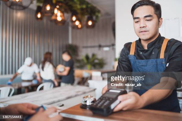 customer hand using credit card for paying bill by using payment machine. - new zealand small business stock pictures, royalty-free photos & images