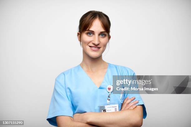 smiling female nurse against gray background - nurse standing stock pictures, royalty-free photos & images