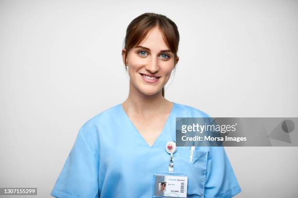 smiling female nurse against white background - id card stock-fotos und bilder