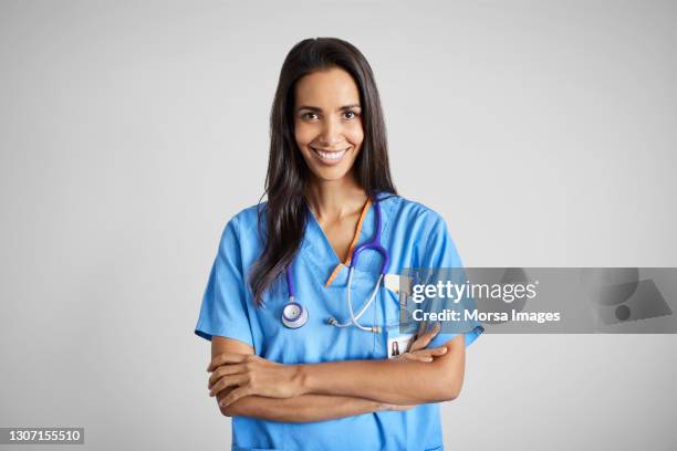 confident mixed race doctor/nurse against white background - nurse and portrait and white background and smiling and female and looking at camera stock-fotos und bilder