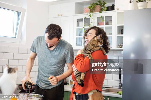 young couple living with cat - young couple cooking stock pictures, royalty-free photos & images