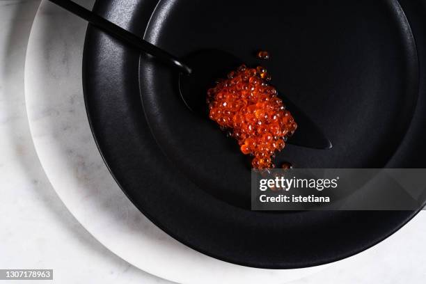 red caviar on cake spatula on black ceramic plate - ikura stock pictures, royalty-free photos & images