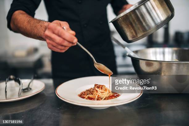chef mâle préparent des pâtes dans la cuisine de restaurants - chef cuisinier sauce photos et images de collection