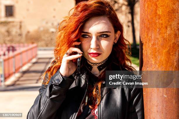 alternative girl with blue eyes and orange hair leaning on a column while making a call with her mobile phone. - gothare bildbanksfoton och bilder