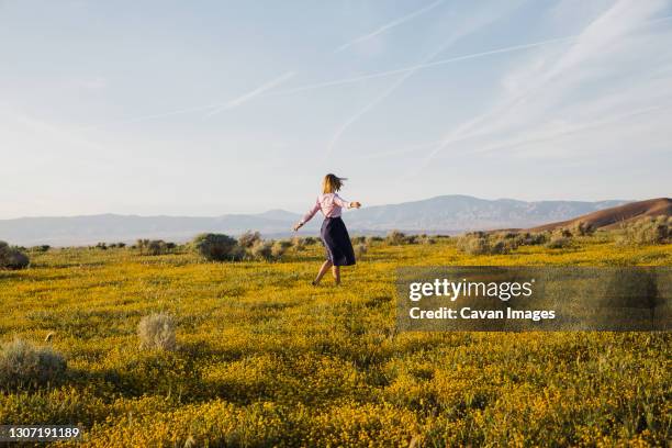 joyful young female dancing in the desert flower field - lancaster california stock pictures, royalty-free photos & images