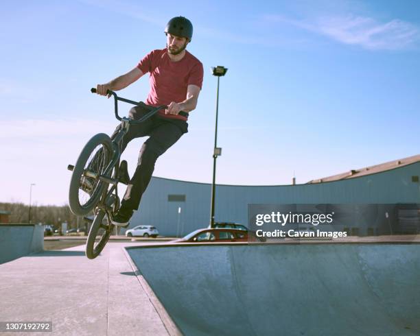 bmx rider mid air coming out of ramp in skatepark on warm summer - bmx stock-fotos und bilder