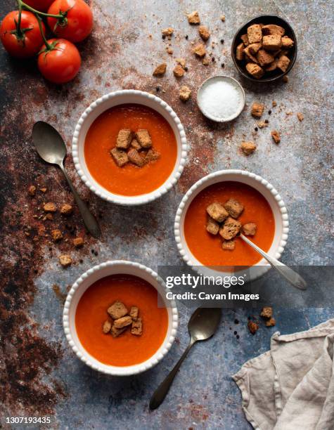 overhead flat lay of bowls of tomato soup on gray stone background. - krutong bildbanksfoton och bilder