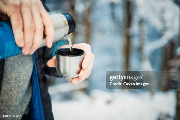 man pouring hot tea in winter forest - tea outdoor stock-fotos und bilder