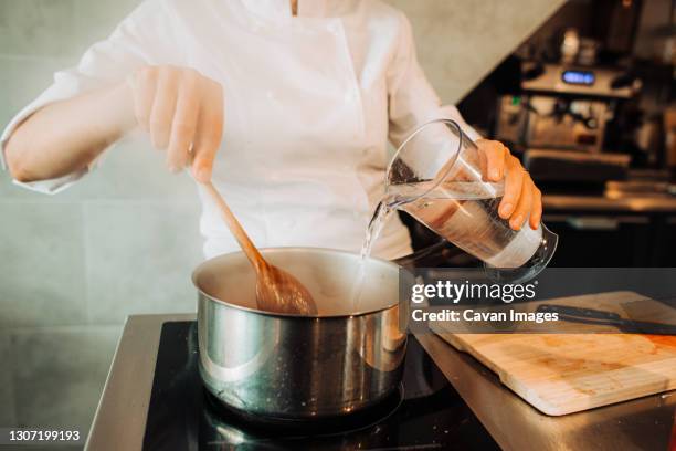 chef pouring water in pan while working in restaurant kitchen - pan stock pictures, royalty-free photos & images