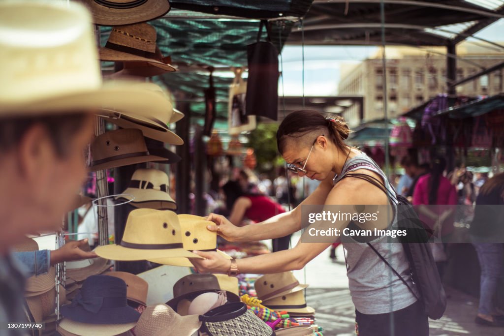 Alternative fit traveller buys hat at Mexican market place