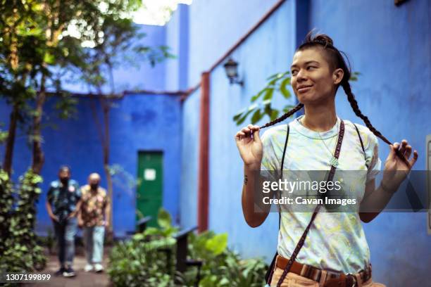 fun alternative young woman holds plaits on summer holiday - androgynous 個照片及圖片檔