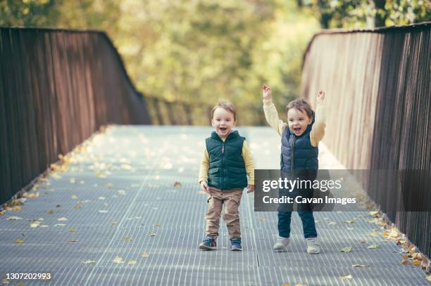 two super positive toddler twin boys on a walk in autumn park - twin boys stock pictures, royalty-free photos & images