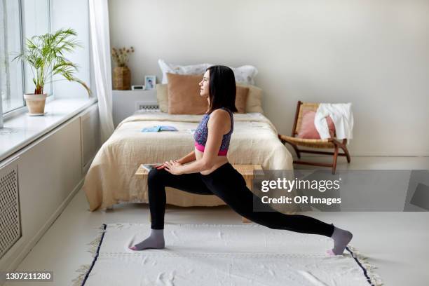 woman doing gymnastics in bedroom at home - lunge imagens e fotografias de stock