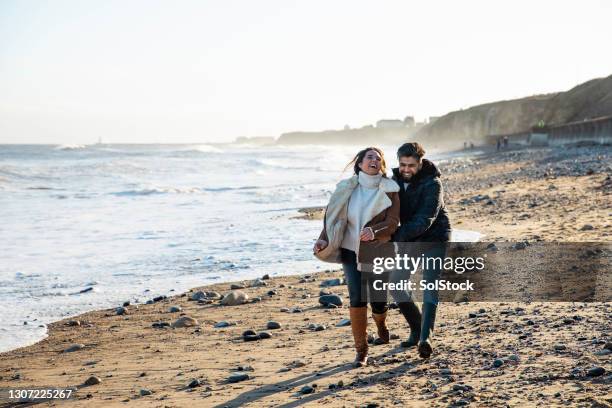 falling in love - romantic couple walking winter beach stock-fotos und bilder