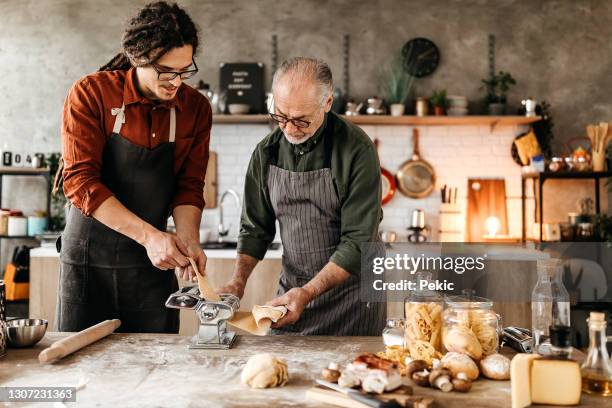 father and son making pasta together in their domestic kitchen - chef demonstration stock pictures, royalty-free photos & images