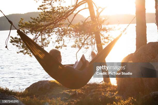 woman reading book on hammock - finland stock pictures, royalty-free photos & images