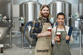 Smiling Workers Holding Beer Glasses at Modern Brewery