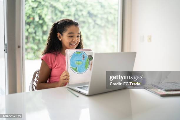 happy girl presenting her planet earth drawing during homeschooling - climate change kids stock pictures, royalty-free photos & images