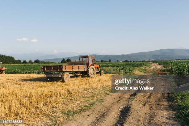 tractor with trailer in open agricultural fields on clear evening - trailer stock-fotos und bilder