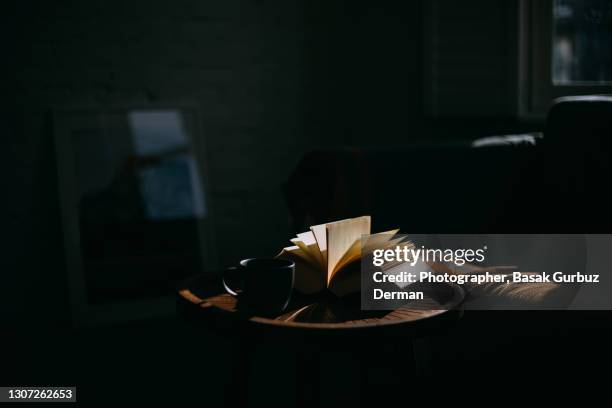 a book on a side table and a cup of coffee - buch tisch stock-fotos und bilder