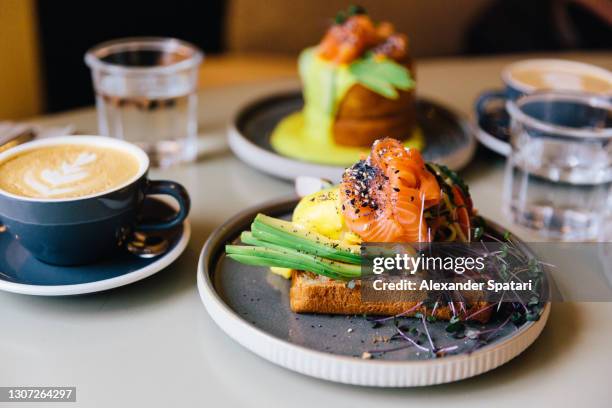 avocado toast with salmon and poached egg served for breakfast at a cafe - the luncheon stock pictures, royalty-free photos & images