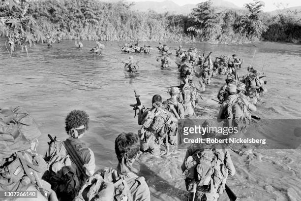Salvadoran Army soldiers from the Atlacatl battalion cross a river during a military operation, San Miguel department, El Salvador, late August or...