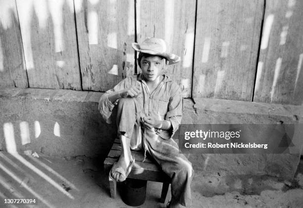 Portrait of a young boy as he sits on a low stool, Ciudad Barrios, San Miguel department, El Salvador, October 23, 1984.