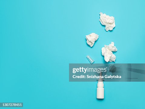 Nasal spray and crumpled wipes on a blue background. Nasal spray and crumpled wipes on a blue background.