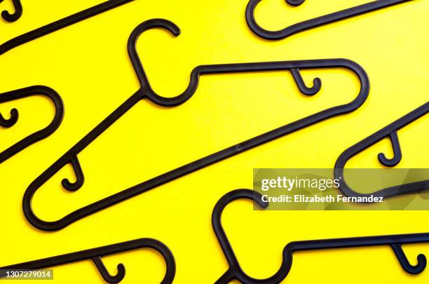 pattern of black plastic hangers on a yellow background. the concept of selling goods, shopping and retail. - coat hanger stock-fotos und bilder