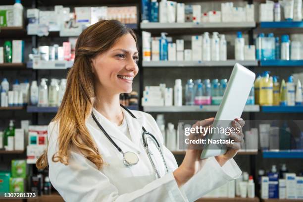 smiling female pharmacist with a digital tablet and stethoscope - female pharmacist with a digital tablet imagens e fotografias de stock