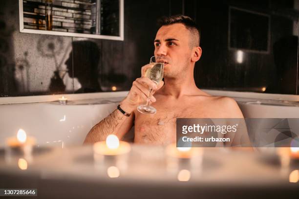 junger mann trinkt champagner in der badewanne - champagne salon stock-fotos und bilder