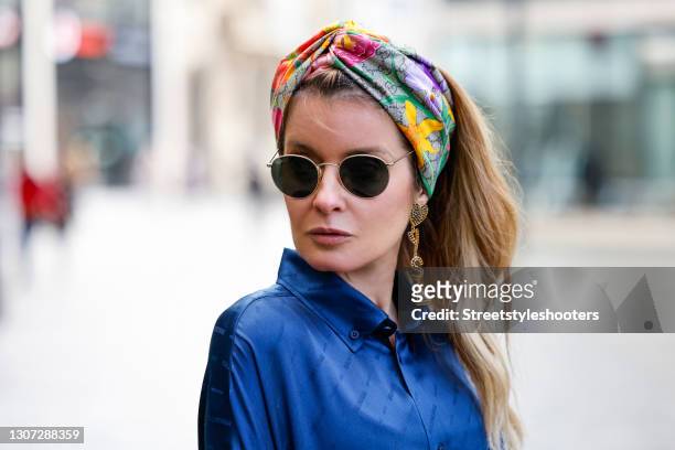 Influencer Gitta Banko wearing a multicolored floral print head scarf by Gucci, a long dark blue silk dress with logo print by Balenciaga, sunglasses...