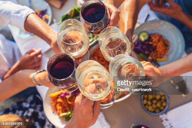 group of friends having a meal outdoors. they are celebrating with a toast using wine - dining stock pictures, royalty-free photos & images