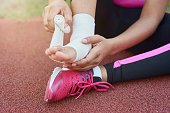 Afro American girl putting bandage on injured foot