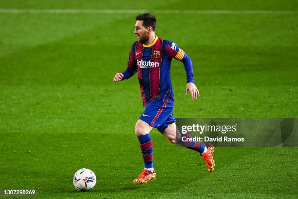 Lionel Messi of FC Barcelona runs with the ball during the La Liga Santander match between FC Barcelona and SD Huesca at Camp Nou on March 15, 2021...