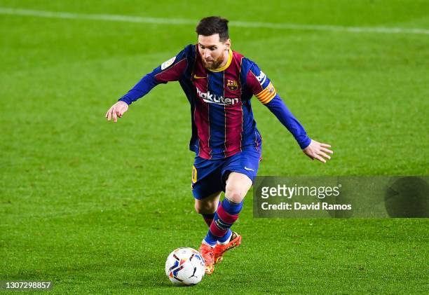Lionel Messi of FC Barcelona runs with the ball during the La Liga Santander match between FC Barcelona and SD Huesca at Camp Nou on March 15, 2021...