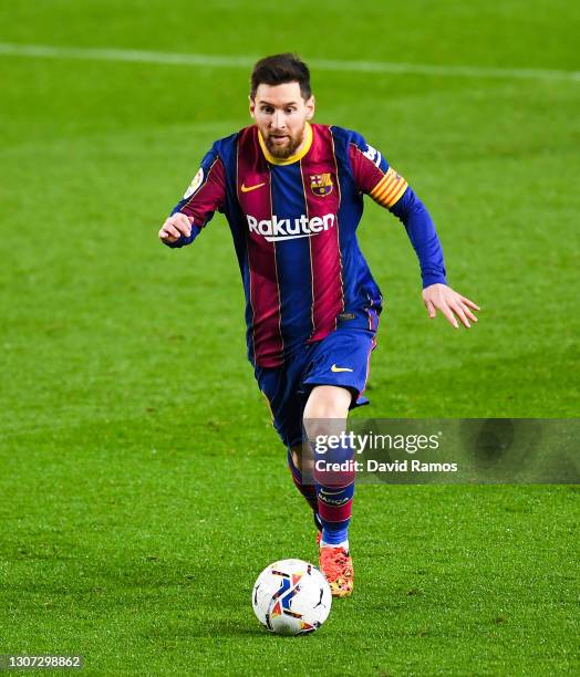 Lionel Messi of FC Barcelona runs with the ball during the La Liga Santander match between FC Barcelona and SD Huesca at Camp Nou on March 15, 2021...