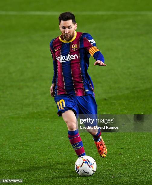 Lionel Messi of FC Barcelona runs with the ball during the La Liga Santander match between FC Barcelona and SD Huesca at Camp Nou on March 15, 2021...